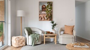 Ein modernes Wohnzimmer mit einer Couch, einem Sessel und einem kleinen Tisch mit Dekoration.