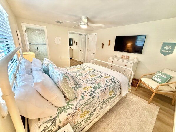 Ein Schlafzimmer mit Bett, Fernseher, Sessel und Deckenventilator.