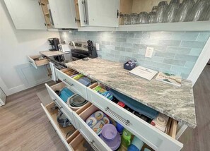 A kitchen with a marble countertop, white cabinets, and a tiled backsplash. - 2 Homes, Steps to Beach, 2 Hot Tubs, 4 Kings. (Indian Rocks Beach)