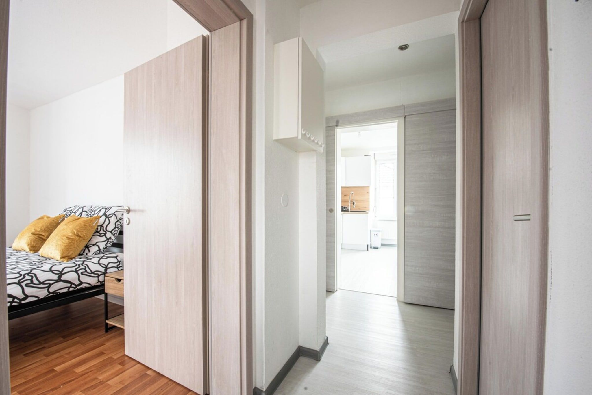 Een slaapkamer met een bed, een kledingkast en een gang die naar een keuken leidt.