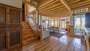 A spacious wooden interior with a staircase, a living area with a sofa, and a dining area.