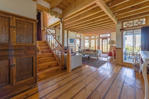 Un interior espacioso de madera con una escalera, una sala de estar con sofá y un comedor.