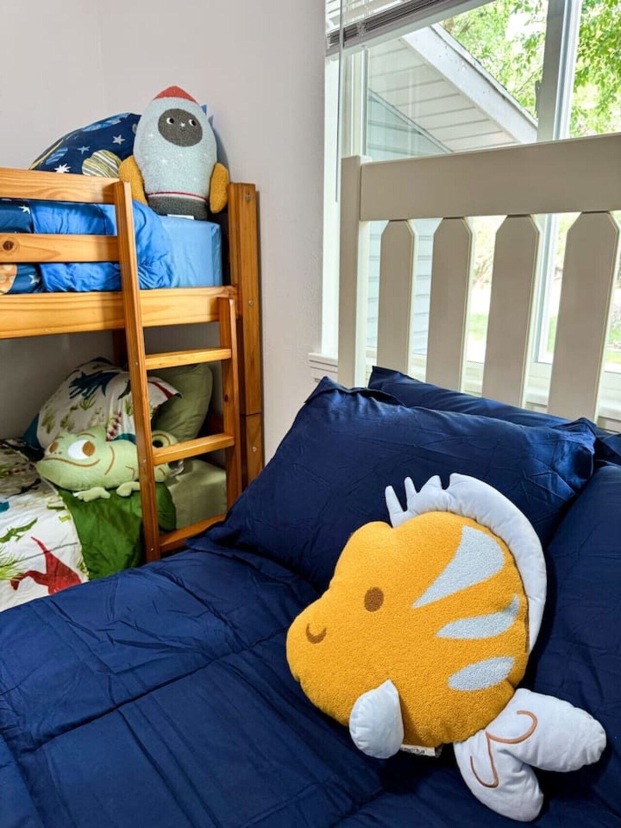 A bunk bed with a window view, a plush toy on the lower bunk, and a ladder.