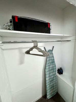 A closet with a hanging rack, a shelf with a bag, and a pair of shoes.