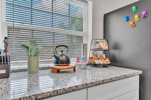 A kitchen counter with a kettle, utensils, and a drink dispenser. - Family & Sports Team Oasis Near Legoland & Parks (Winter Haven)