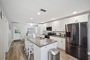 A modern kitchen with white cabinets, stainless steel appliances, and a granite countertop. - Family & Sports Team Oasis Near Legoland & Parks (Winter Haven)