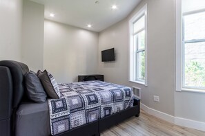A bedroom with a bed, a TV mounted on the wall, and a window. - Charming 1-bedroom apartment with AC in vibrant Brooklyn (Brooklyn)
