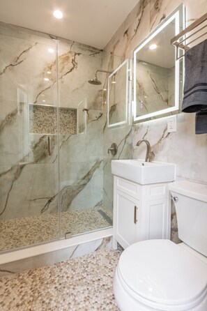 A bathroom with a glass-enclosed shower, a white sink, and a toilet. - Charming 1-bedroom apartment with AC in vibrant Brooklyn (Brooklyn)