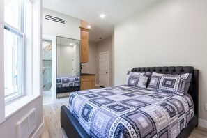 A bedroom with a large bed, a window, a mirror, and a door. - Charming 1-bedroom apartment with AC in vibrant Brooklyn (Brooklyn)
