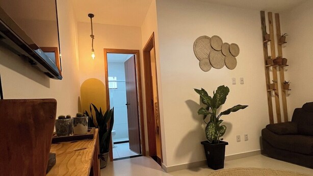 Una sala de estar con un banco de madera, una planta en maceta, un tapete redondo y un estante con plantas.