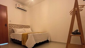 Un dormitorio con cama, aire acondicionado, una escalera de madera y una puerta.