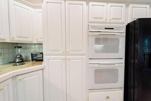 Eine Küche mit weißen Schränken, einem schwarzen Kühlschrank und einer Arbeitsplatte mit Mixer und Toaster.