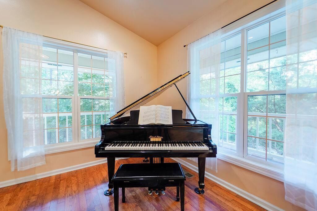 Un piano de cola en una habitación con amplios ventanales y suelo de madera.