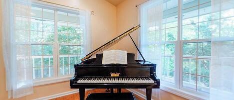 Un piano de cola en una habitación con amplios ventanales y suelo de madera.