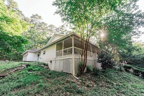 Una casa con un portico, circondata da alberi e vegetazione.