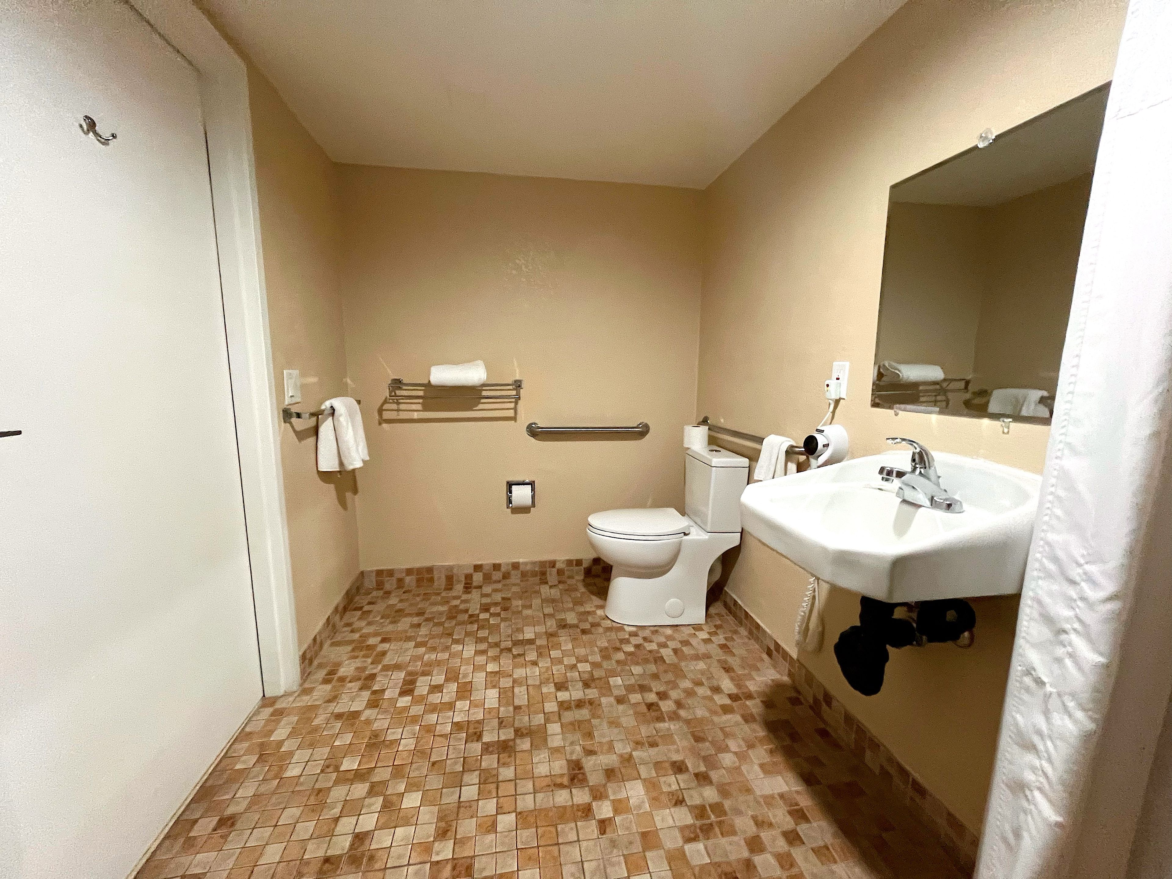 A small bathroom with a toilet, sink, and a mirror.