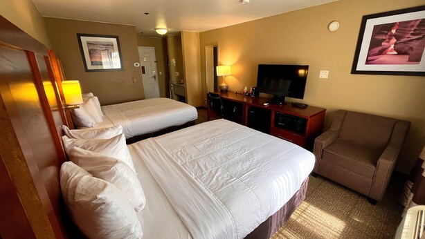 A hotel room with two beds, a television, a desk, and a chair.