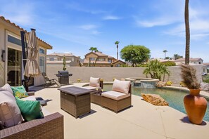 Eine Terrasse im Freien mit Korbmöbeln, einem Grill und einem Swimmingpool.