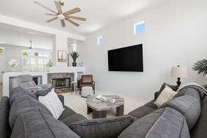 Un salon moderne doté d’une cheminée, d’un téléviseur à écran plat et d’un ventilateur de plafond.
