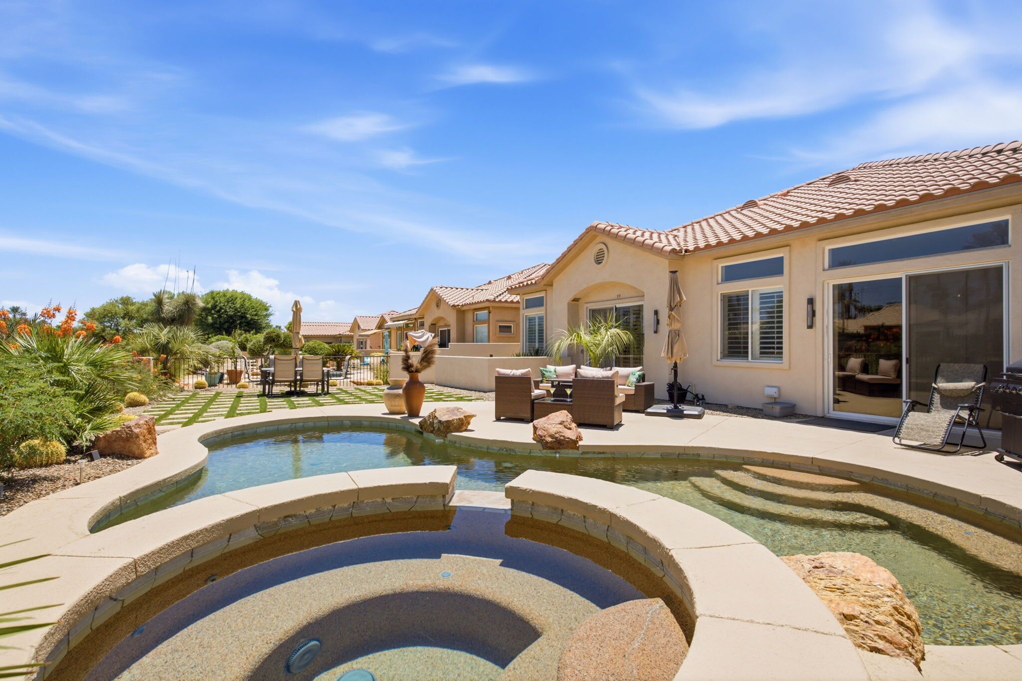 A residential property with a swimming pool, outdoor seating, and a landscaped garden.