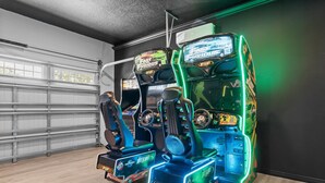 En række arkademaskiner med racer-spil og 'The Fast and the Furious'-branding, placeret i et rum med garageport og trægulv.