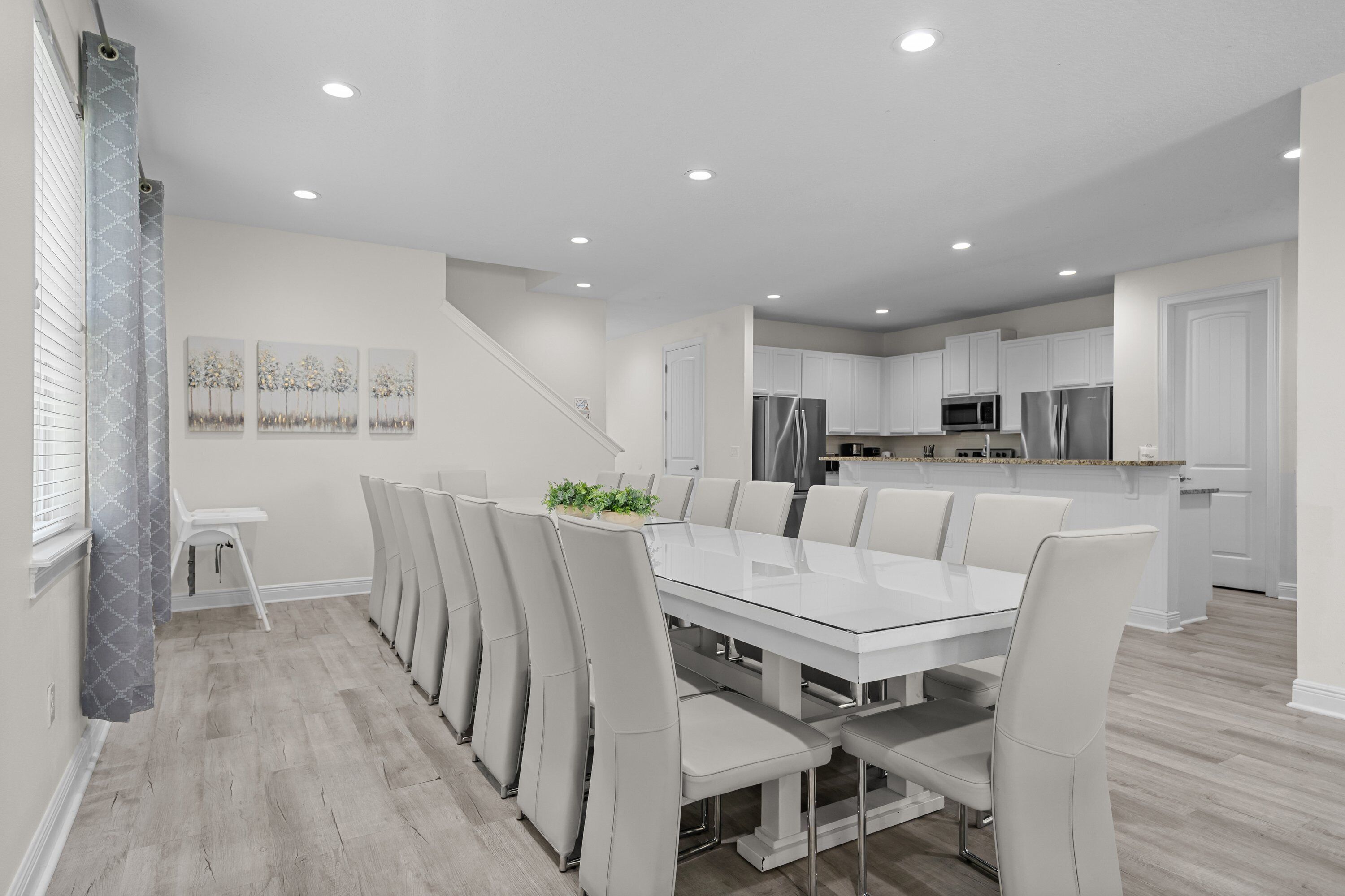 A modern kitchen with white cabinets, stainless steel appliances, and a dining area with a glass table and chairs.