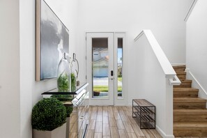 Ein modernes Interieur mit Treppe, einer Glastür zum Außenbereich und minimalistischem Design.