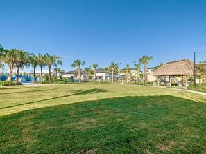 A well-maintained grassy area with palm trees and a thatched-roof structure, likely a part of a resort or hotel. - Family-Friendly 4BR ChampionsGate Retreat with Private Pool Near Disney (Davenport)