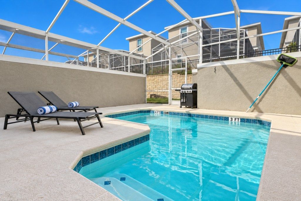 Private screened pool with loungers and gas grill.