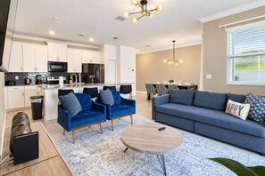A modern living room with a sofa, two armchairs, a coffee table, and a dining area with a table and chairs. - Family-Friendly 4BR ChampionsGate Retreat with Private Pool Near Disney (Davenport)