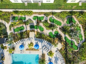 Vista aérea de um resort com vários campos de golfe, piscina e áreas de lounge.