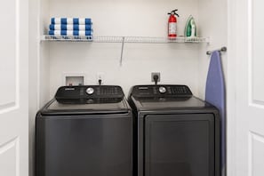 Laundry closet with washer, dryer, ironing board, and towels. - Family-Friendly 4BR ChampionsGate Retreat with Private Pool Near Disney (Davenport)