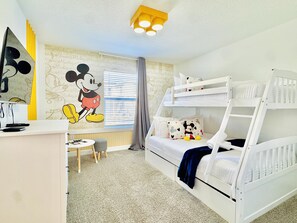A child's room with bunk beds, a Mickey Mouse mural, a desk with a computer, and a window with blinds. - Family-Friendly 4BR ChampionsGate Retreat with Private Pool Near Disney (Davenport)