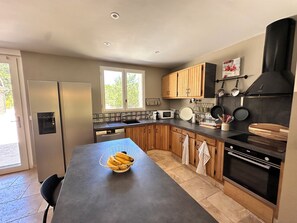 Une cuisine moderne équipée d’un réfrigérateur, d’un four à micro-ondes, d’un four et de meubles de rangement en bois.