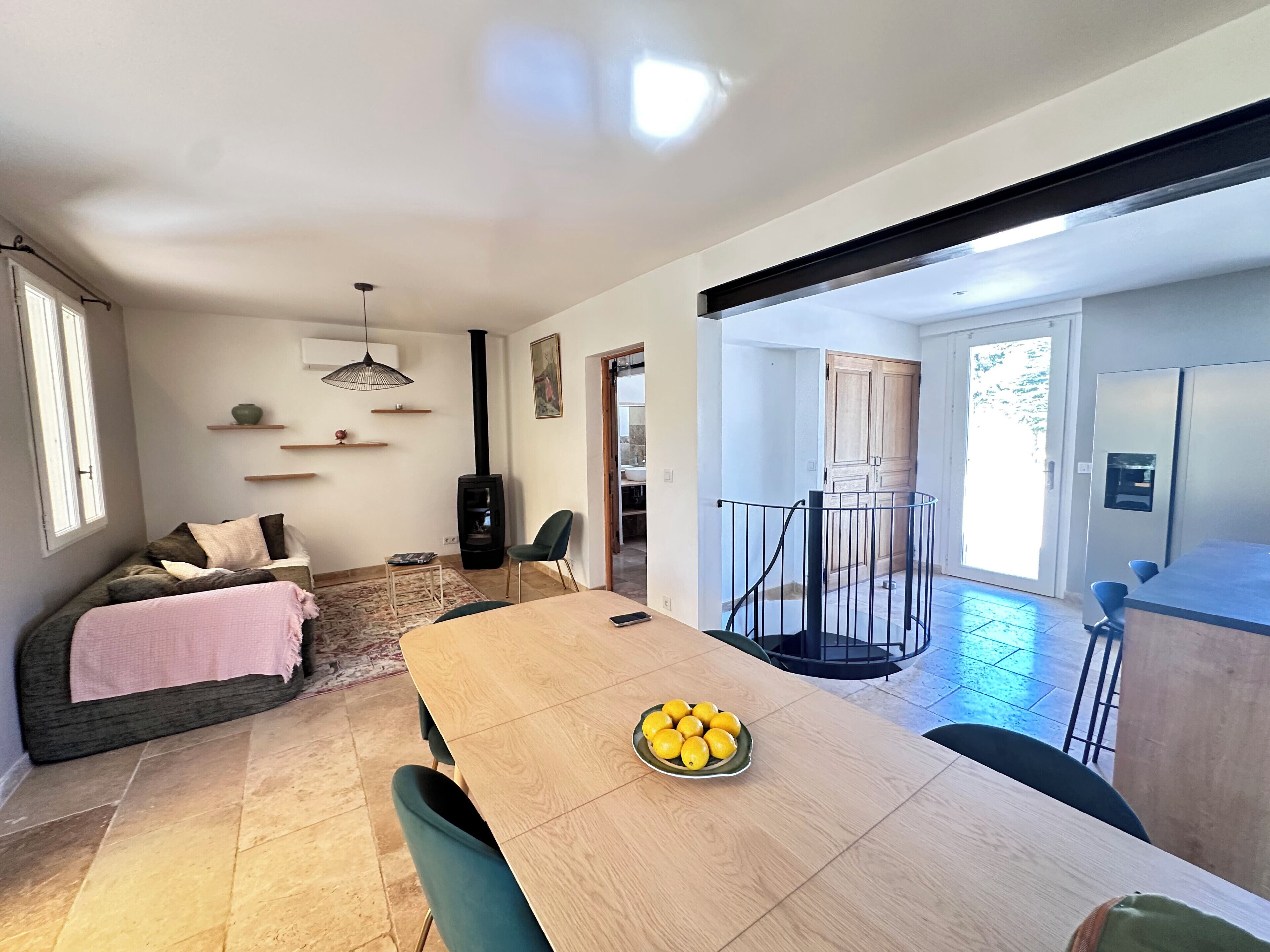 A modern living space with a dining area, a sofa, a fireplace, and a view of the outside.
