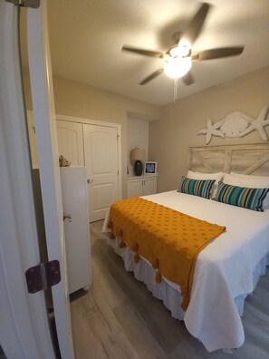 Ein Schlafzimmer mit einem Bett, einem Deckenventilator, einer Tür und einer Wand mit einer Meerstern-Dekoration.