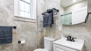Een badkamer met toilet, wastafel, handdoekhouder en spiegel.