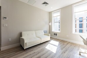 A modern living room with a white sofa, large windows, and a light-colored floor. - Stylish Brooklyn Apartment Natural Light (Brooklyn)