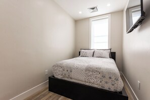 A bedroom with a bed, a window, and a wall-mounted air conditioning unit. - Stylish Brooklyn Apartment Natural Light (Brooklyn)