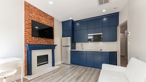 Een moderne keuken met blauwe kastjes, een flatscreen televisie en een witte bank.