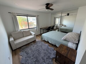 A bedroom with a bed, a sofa, a desk, and a ceiling fan. - Pacific Beach Retreat Bay Views + Hot Tub (San Diego)
