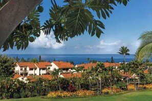 A resort with multiple buildings, palm trees, and a view of the ocean. - Spacious 3-bedroom condo in a peaceful location with AC and gym (Kailua-Kona)