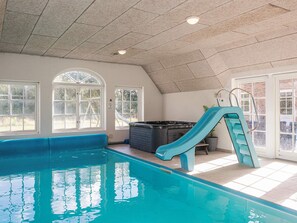 An indoor swimming pool with a slide, large windows, and a sauna. - 4 Star Holiday Home in Ulfborg (Ulfborg)