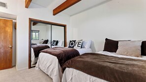 A bedroom with two beds, a large mirror, and a wardrobe. - Golden Hour Lodge by Avantstay BBQ + Great Room + Multiple Decks Lake & Sunset Views (Lake Arrowhead)