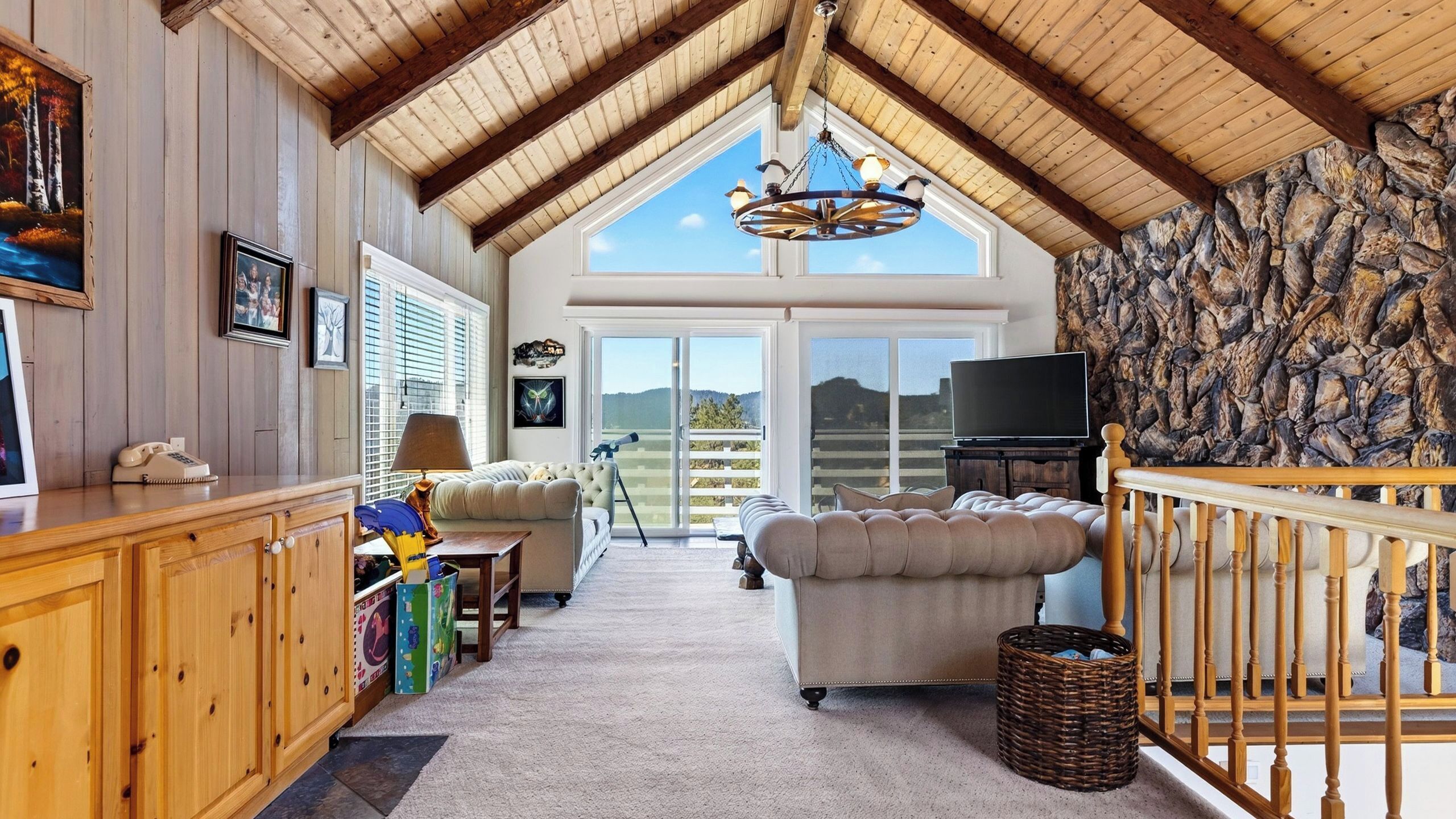 Un vaste espace de vie de style loft, doté d’un haut plafond, d’une grande fenêtre et d’un mur en pierre.
