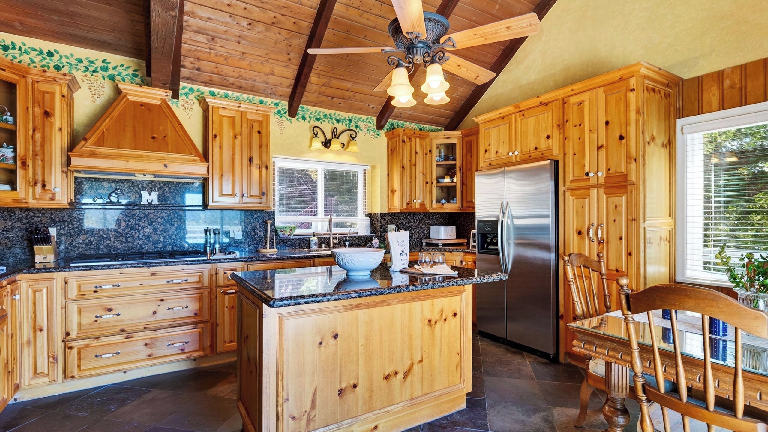 A kitchen with wooden cabinets, a central island, a refrigerator, and a ceiling fan.