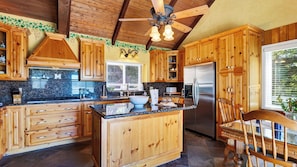 A kitchen with wooden cabinets, a central island, a refrigerator, and a ceiling fan.