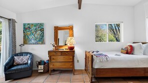 Ein Schlafzimmer mit einem Bett, einem Schminktisch, einem Sessel und einem Fenster.
