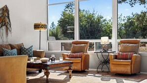 Un salon avec des fauteuils en cuir, une table basse et une lampe.