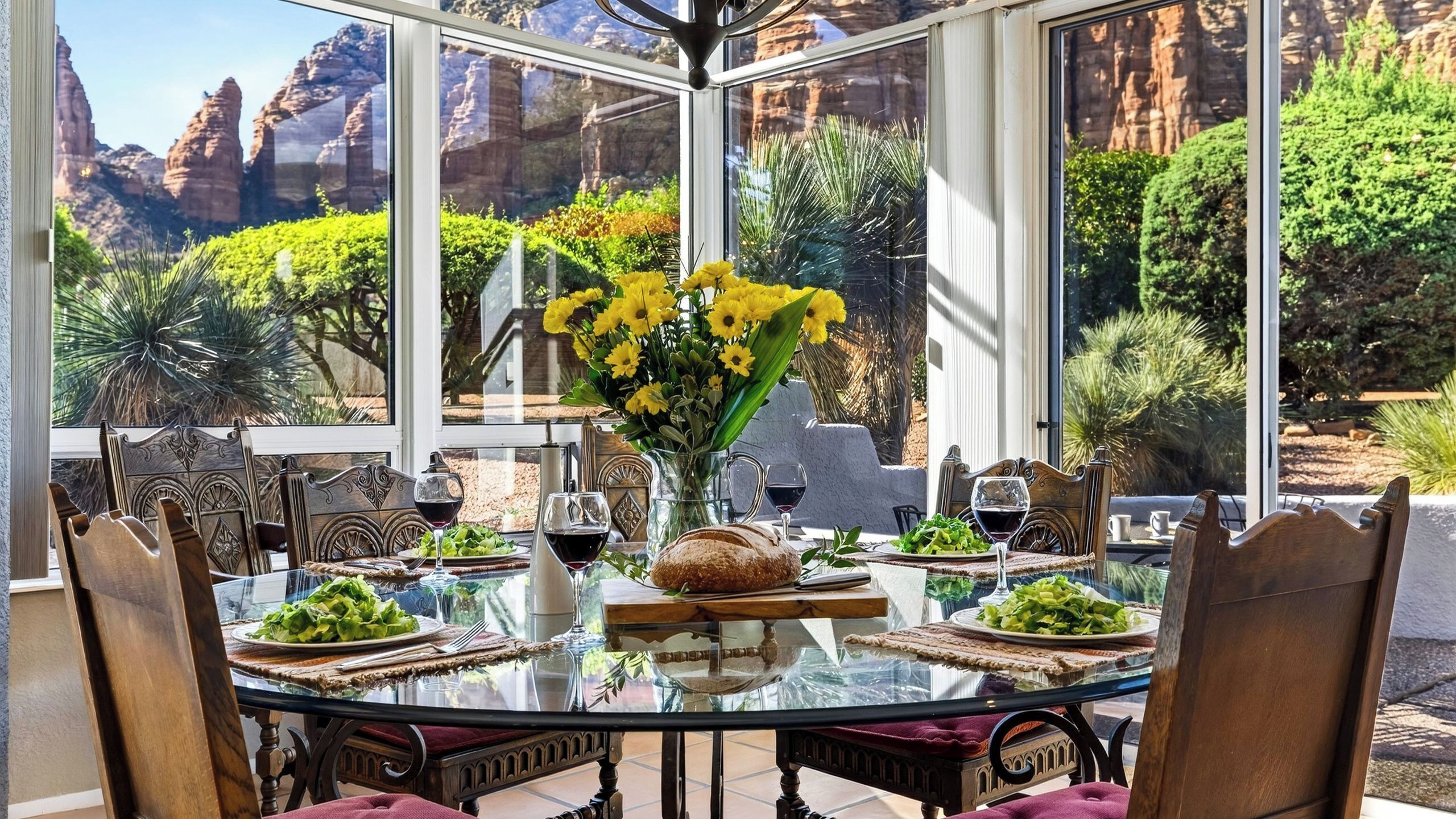A dining area with a glass table, chairs, and a view of red rock formations.